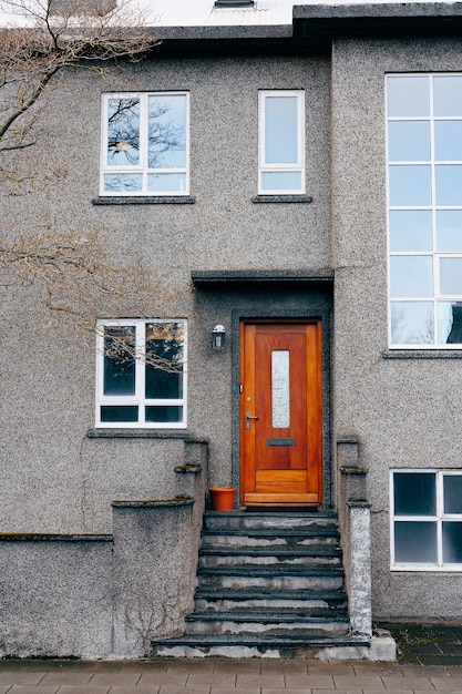 The entrance is from a wooden door into a modern two-story building with plastic windows of various