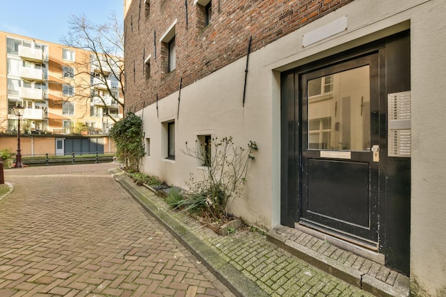 Entrance to a multistorey residential building with windows of various formats and a tiled path in front of the house