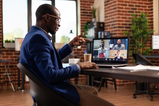 Imprenditore che partecipa a una riunione di lavoro in videochiamata con i colleghi per lavorare sul progetto. dipendente che utilizza la videoconferenza online sul laptop per pianificare l'avvio con i colleghi in ufficio.