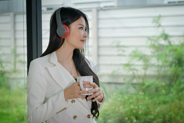 Entrepreneur, beautiful woman drinking coffee and listening to music during lunch breaks