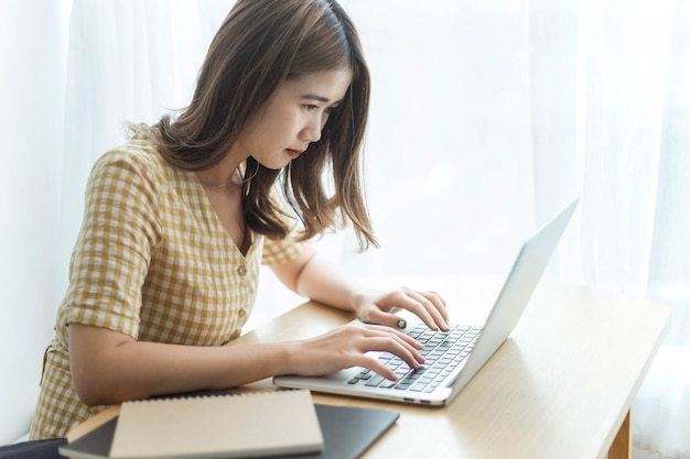 Entrepreneur concept a young female freelancer working on her laptop device typing an urgent document seriously.