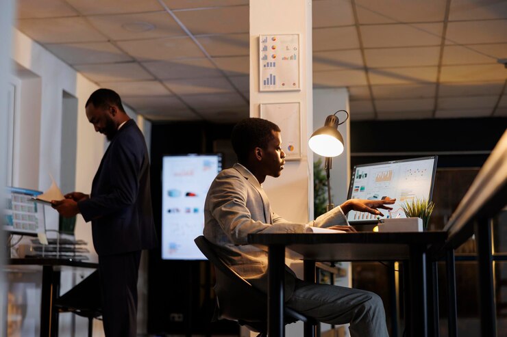 Photo entrepreneur man looking at marketing graphs report on computer, working overhours at financial strategy. employee trying to increase company profit in startup office. business concept