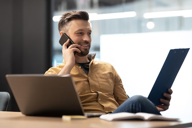 Entrepreneur Man Talking On Phone Holding File Binder In Office