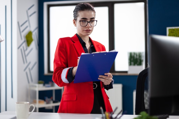 Imprenditore in piedi nel posto di lavoro dell'ufficio aziendale a prendere appunti