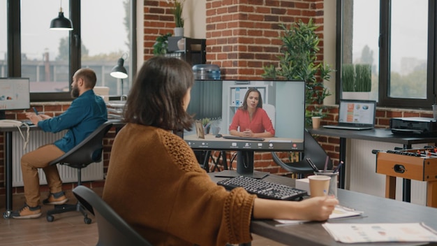 Entrepreneur talking to manager on video call about business project and planning. Woman using online video conference on computer to talk to colleague about data and information at office.