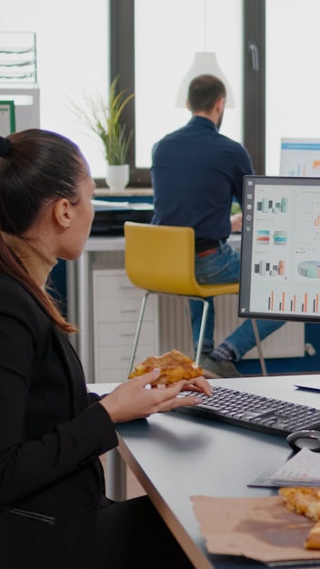 Entrepreneur woman having meal break sitting at table eating pizza slice fastfood delivery. Takeaway delivery lunch order package delivered at company office. Takeout food at lunchtime eating at desk