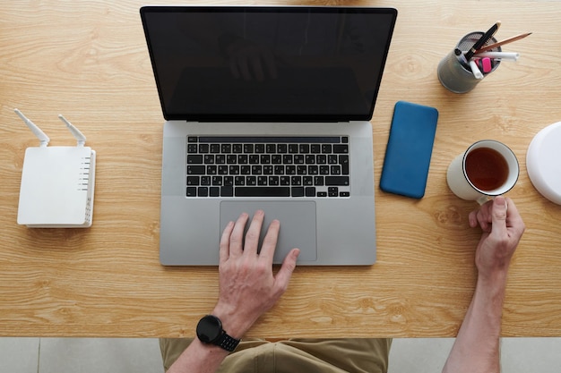 Entrepreneur working on laptop and drinking coffee view from above