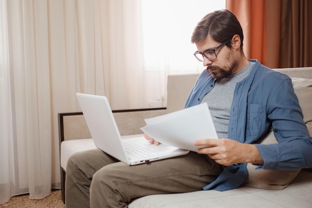 Предприниматель работает с ноутбуком и хранит документ в домашнем офисе
