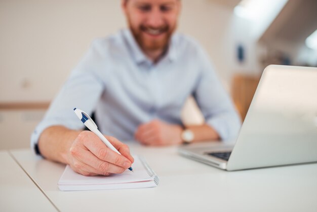 Entrepreneur writing notes sitting at his desk.