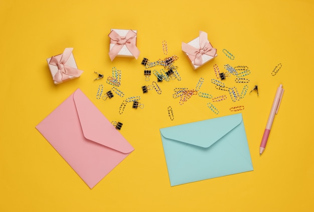 Envelop, geschenkdozen en paperclips op gele achtergrond. Bovenaanzicht