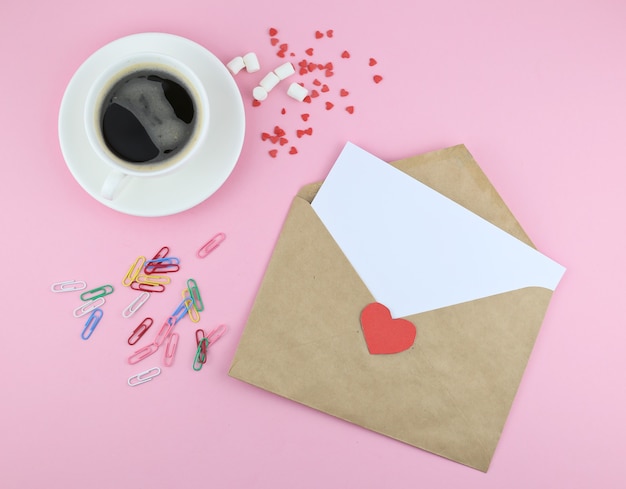 envelop mail met rood hart en kopje koffie op roze achtergrond