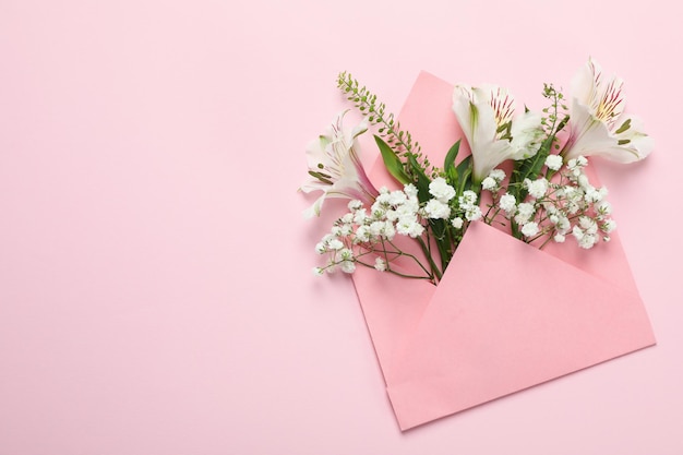 Envelop met bloemen op roze achtergrond, ruimte voor tekst