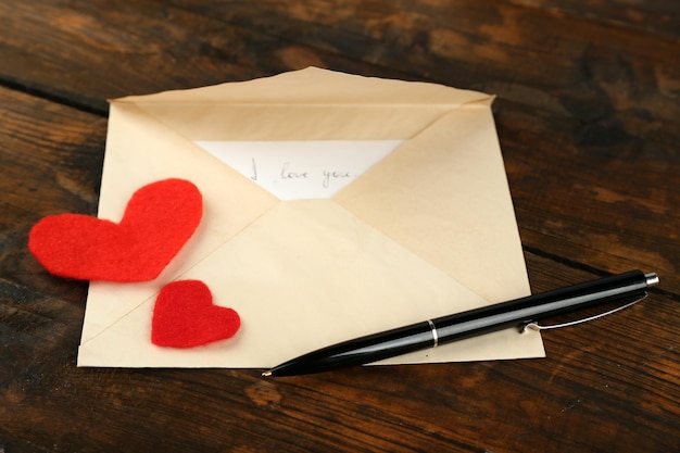 Envelop met hartjes en pen op rustieke houten tafel achtergrond