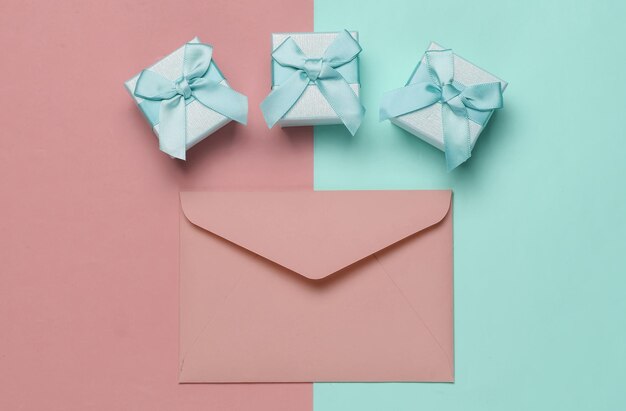 Envelope boxes of gifts on pink blue pastel background Christmas Valentines day wedding or birthday Top view