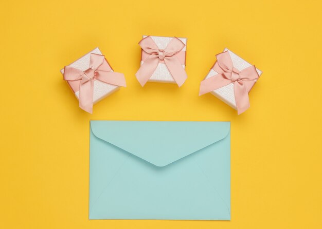 Envelope, boxes of gifts on yellow background. Christmas, Valentine's day, birthday. Top view