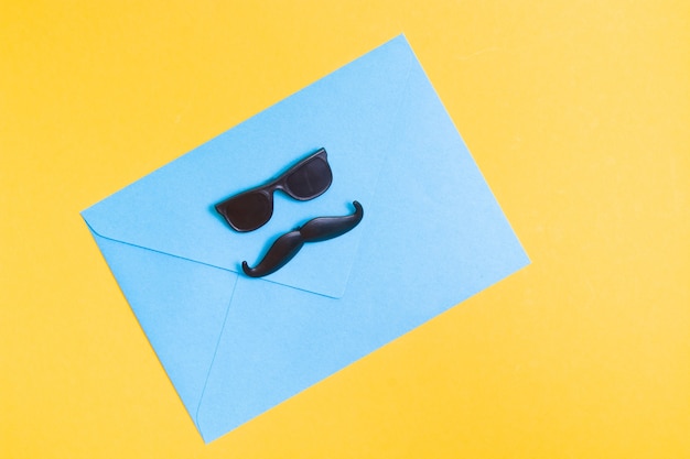 envelope glasses and plastic mustache on yellow background fathers day concept