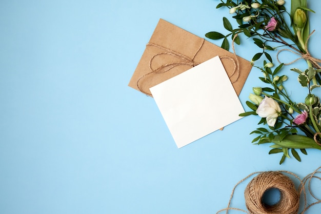 Envelope, paper card and flowers on blue background.