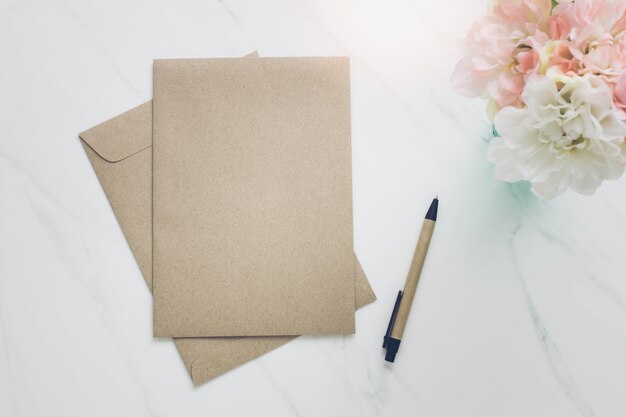 Envelope,pen and flower on white marble table background.