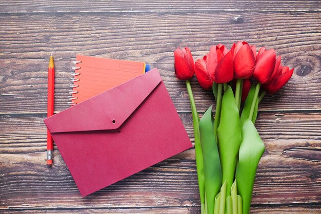 Envelope and red tulip on table