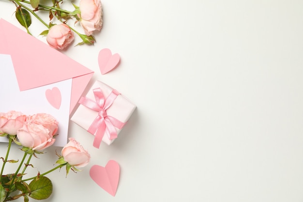 Envelope, roses, hearts and gift box on white background