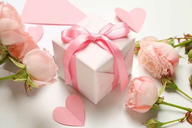 Busta, rose, cuori e confezione regalo su sfondo bianco