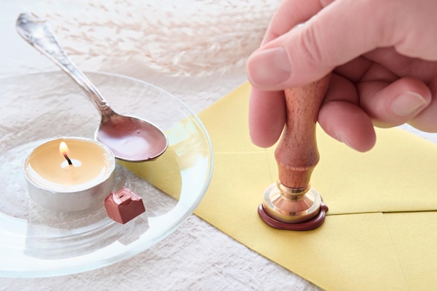 Envelope wax seal with carnation flowers on white table Hand holding stamp