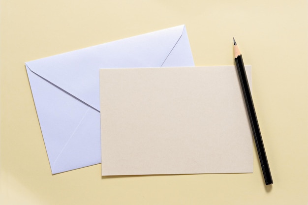 Envelope with blank paper and pencil over beige background