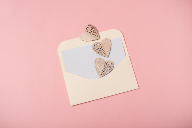 An envelope with a blank sheet and wooden hearts. Valentine's Day concept.