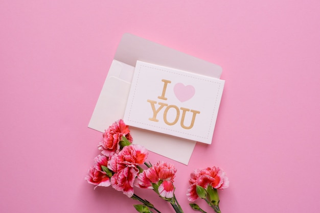 An envelope with card I love you and pink flowers on pink