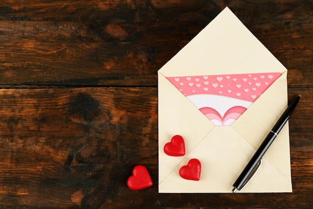 Envelope with hearts and pen on rustic wooden table background