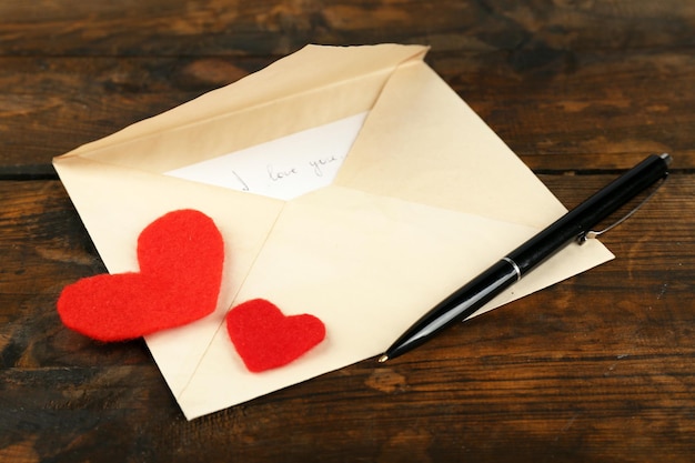 Envelope with hearts and pen on rustic wooden table background