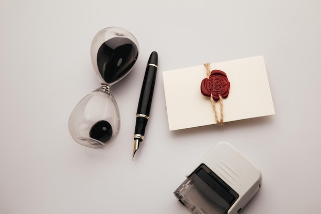 Envelope with wax seal stamp and hourglass on a table