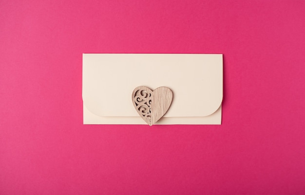 An envelope with a wooden heart on it. flat lay, top view.\
romantic love letter for valentine\'s day concept.