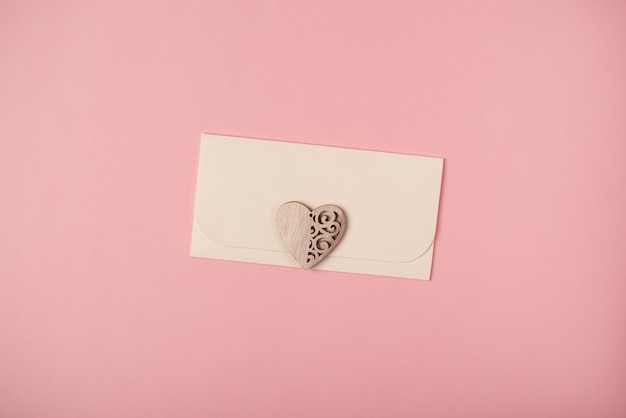 Photo an envelope with the wooden heart. valentine's day concept. flat lay, top view.