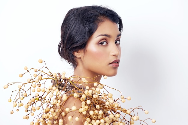 Enveloped in natural beauty studio shot of an attractive young ethnic woman with foliage over her sh