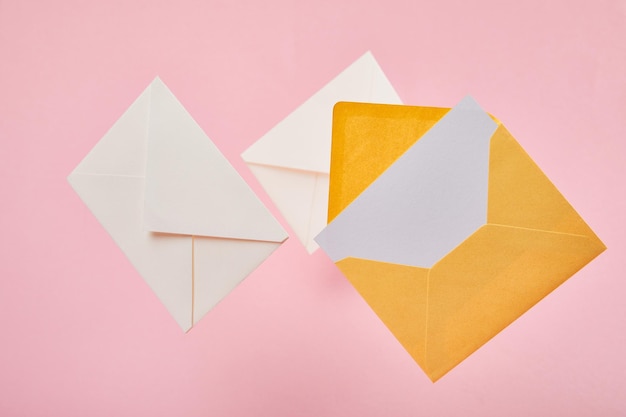 envelopes with blank white card on pink background