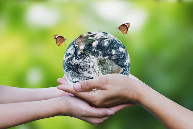 Foto giorno dell'ambiente e concetto della giornata della terra due mani umane che tengono il globo terrestre con una farfalla che vola sopra il mondo dimostra cura e risparmio per il mondo elementi di questa immagine forniti dalla nasa