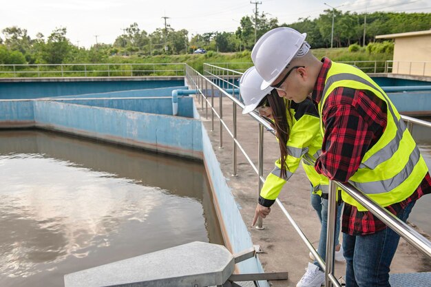 環境エンジニアが廃水処理プラントで働く水供給エンジニアリングが再利用のための水リサイクルプラントで働く技術者とエンジニアが一緒に仕事について話し合う