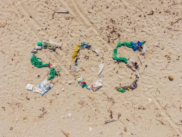 사진 환경 문제 생태 개념 해변에 sos 쓰기가 있는 플라스틱 해변에 흘린 쓰레기
