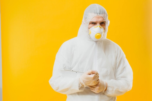 Photo epidemiologist in a mask and hazmat suit on yellow wall