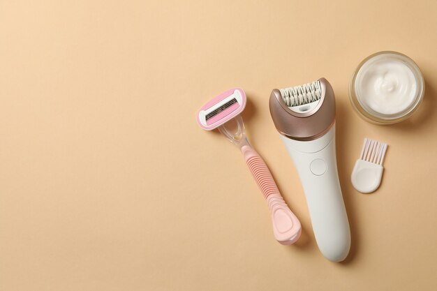 Epilator, scheermes en crème op beige