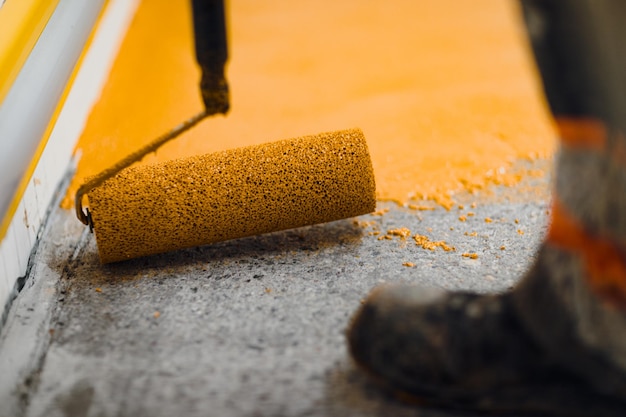 Foto l'applicatore di pavimenti epossidici esegue lavori di verniciatura con malta epossidica poliuretanica