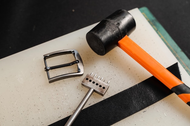 Equipment for genuine leather belt production on the table in the workshop Genuine leather belt buckle hammer and line punch Tools of craftsman for belts creation