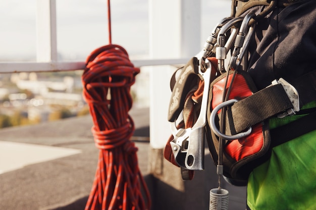 Attrezzature di alpinismo industriale lavoratore sul tetto dell'edificio durante il lavoro industriale a molti piani. attrezzatura da arrampicata prima di iniziare il lavoro. accesso operaio su corda. concetto di opere urbane. copia spazio