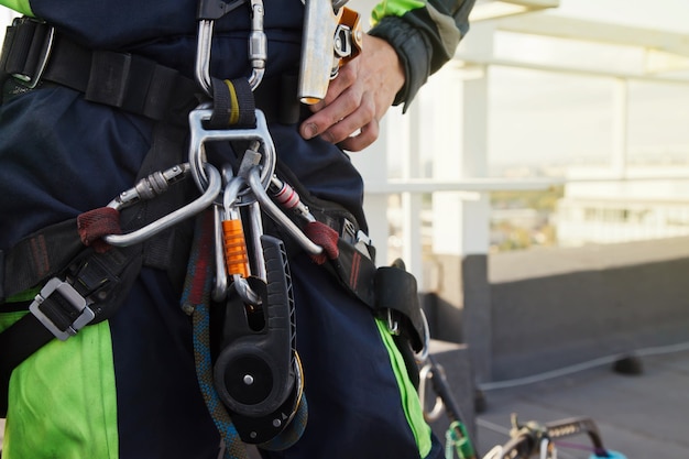 Equipment of industrial mountaineering worker on roof of building during industrial high-rise work. Climbing equipments before starting job. Rope laborer access. Concept of urban works. Copy space