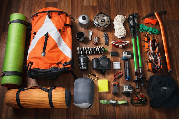 Equipment necessary for mountaineering and hiking on wooden background