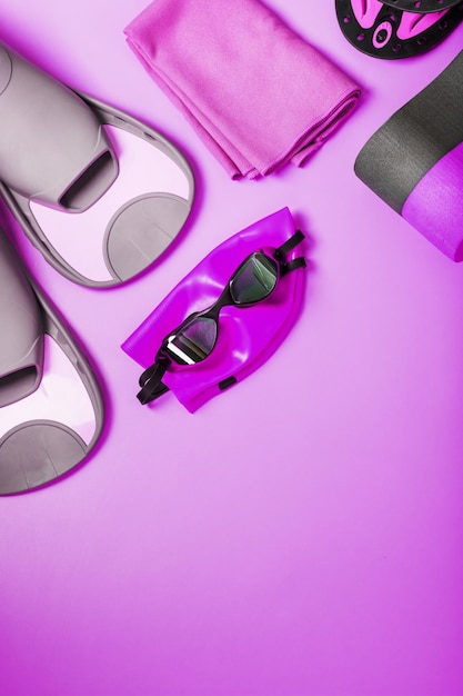 Equipment for swimming in the pool and in the sea on a pink background