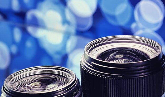 Equipment videographer and photographer. Lenses on the table against the background of bright lamps. Glare and bokeh in the reflection of the camera glass.