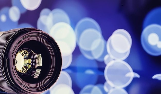 Equipment videographer and photographer. Lenses on the table against the background of bright lamps. Glare and bokeh in the reflection of the camera glass.