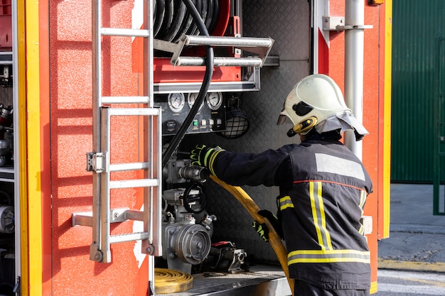 Equipped firefighter handling a water extraction pump, inside a fire truck